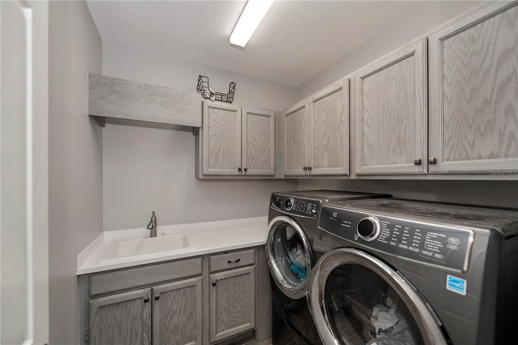 Large inside laundry room with plenty of storage and utility sink