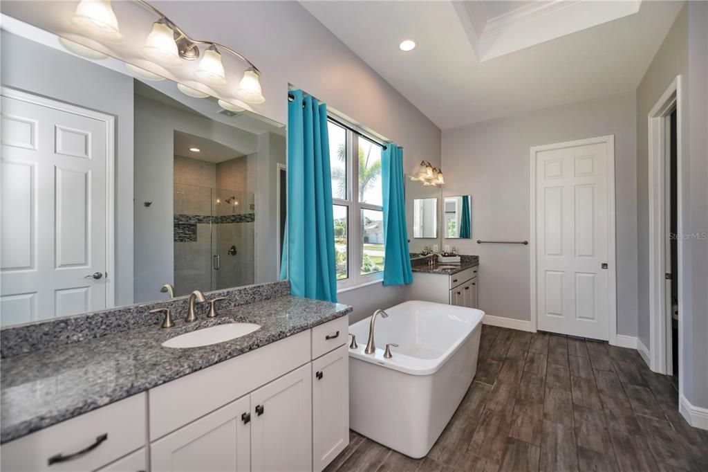 The en-suite bathroom showcases split vanities with dual sinks and granite counters