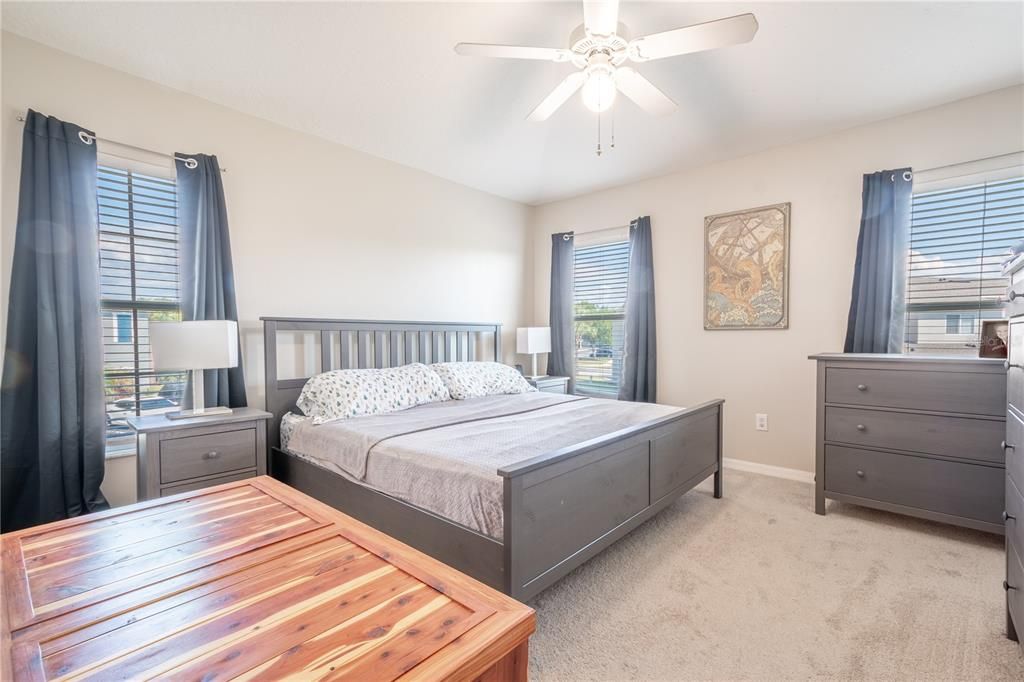 The primary bedroom features plush carpet, neutral tones, a ceiling fan and a ensuite bath.