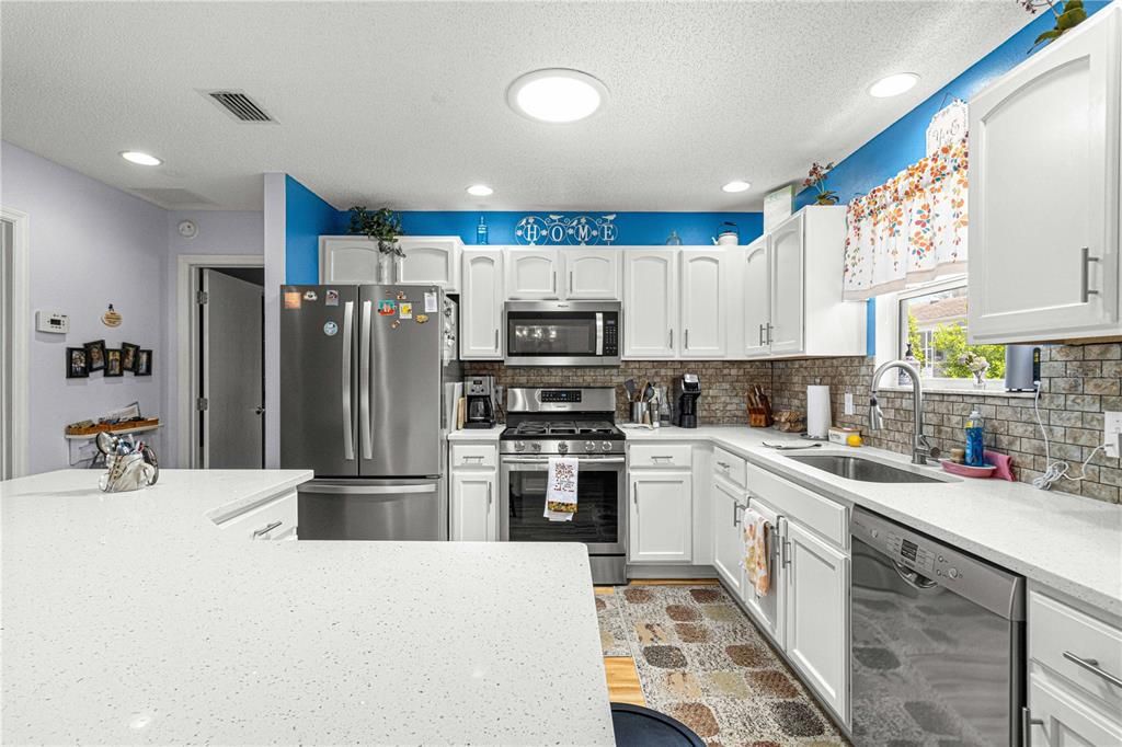 Beautiful Kitchen with SS Appliances, Quartz Counters, Tiled Backsplash and a Large Solar Tube Providing Lots of Natural Light. This Home has Gas Heat, Gas Cooking and a Gas Hot Water Heater