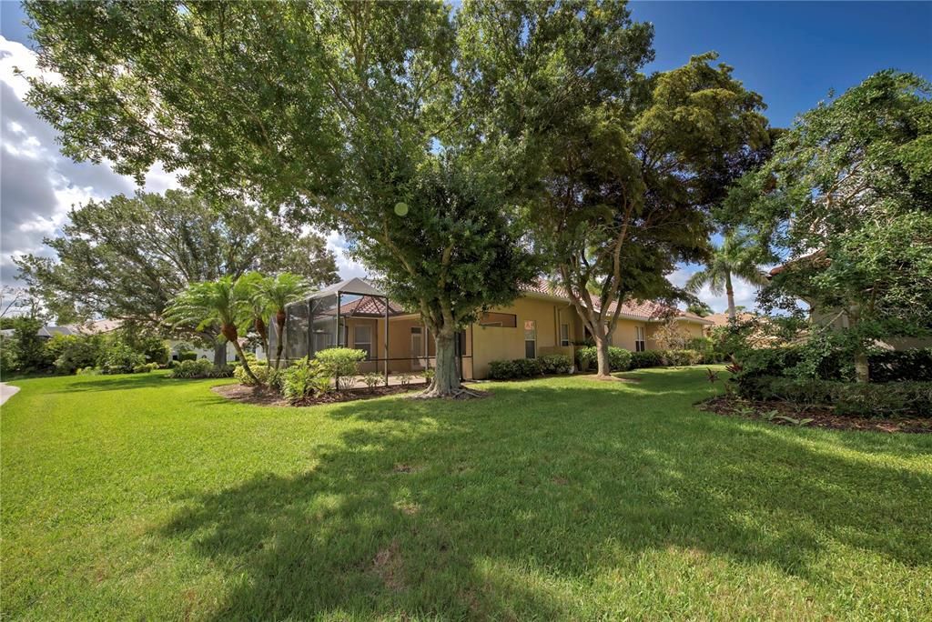 View from another side of the back of the home with mature trees and lush landscaping.