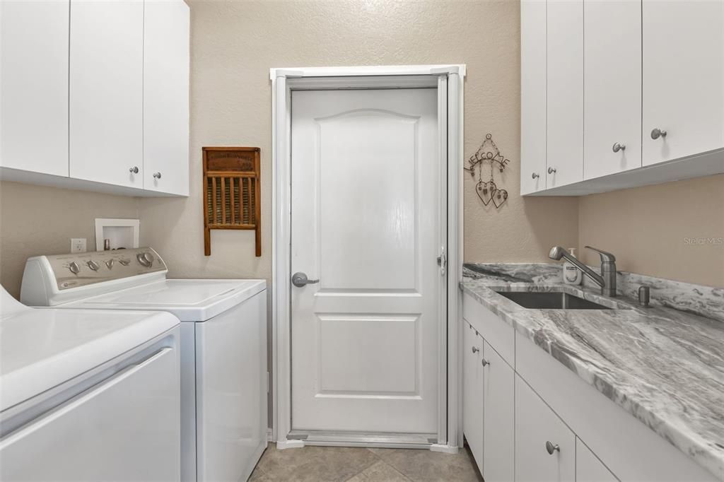 Inside laundry room with washer & dryer, utility sink and extra cabinets.