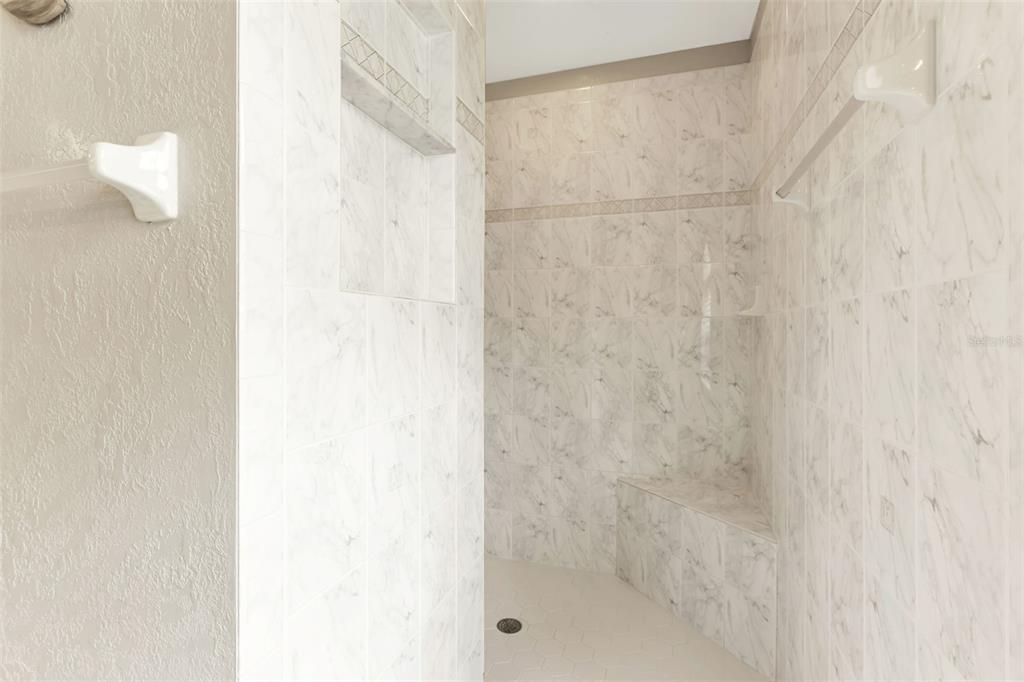 Master bathroom features a beautiful tiled walk in shower  with bench seating.