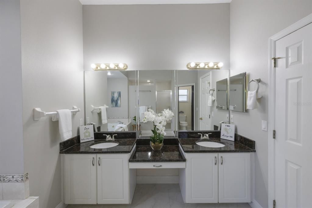Large vanity with two sinks, a wall of mirrors and a linen closet.