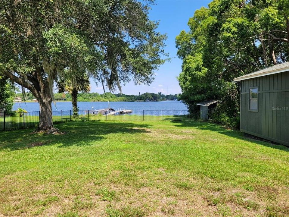 View of lake with 3 sheds/workshops and dock and lots of space under the shaded trees to relax