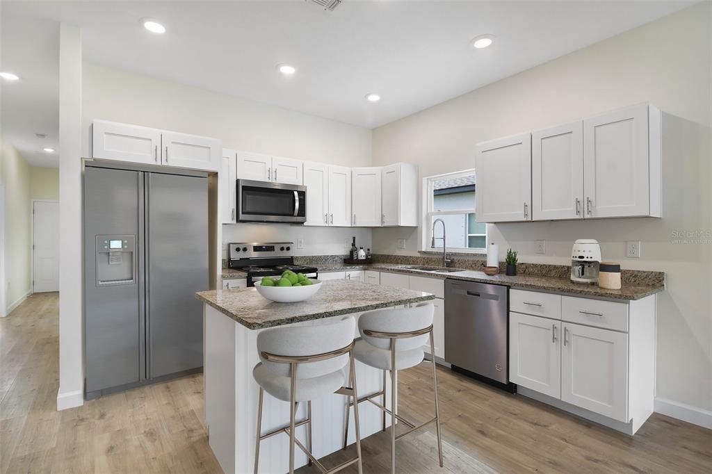 A light and bright OPEN CONCEPT delivers a spacious kitchen featuring desirable shaker style cabinetry, ISLAND with breakfast bar seating and beadboard accent, GRANITE COUNTERS and pantry for ample storage. Virtually Staged/Fridge is virtually staged.