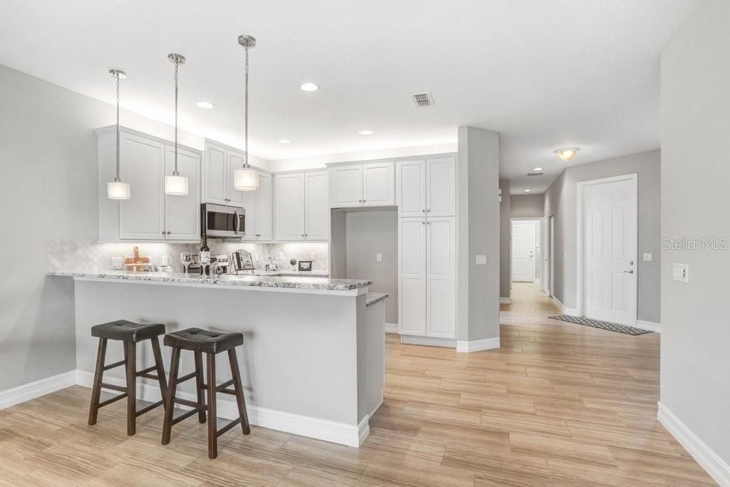 The Kitchen features a bar with overhead pendant lighting that seats up to four.... Granite countertops.... Stainless Steel appliances.... 42" SOFT CLOSE cabinets with crown molding.... and a beautiful, upgraded backsplash!