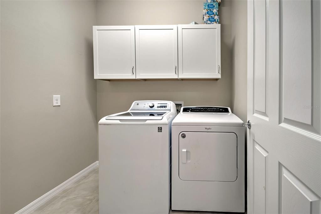 Dedicated laundry room with cabinets for storage.