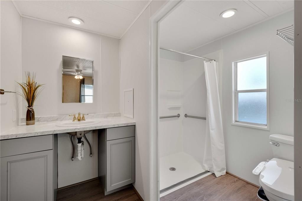 Updated Main bathroom has new vanity, walk-in shower wheelchair accessible, and updated toilet.