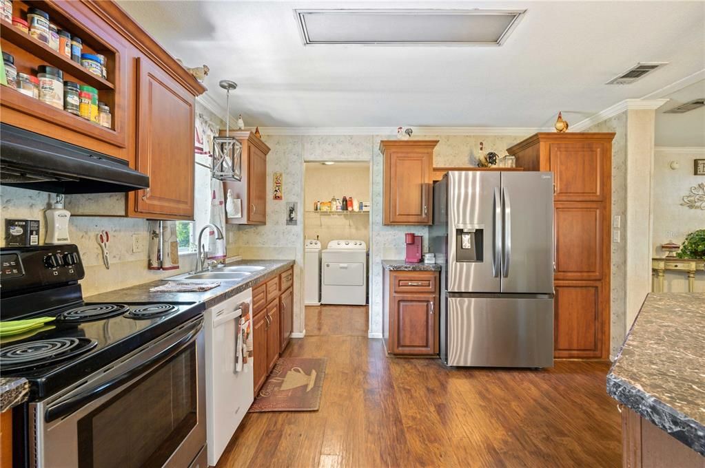 Kitchen has stainless steel appliances, laminate flooring, and ample storage space.