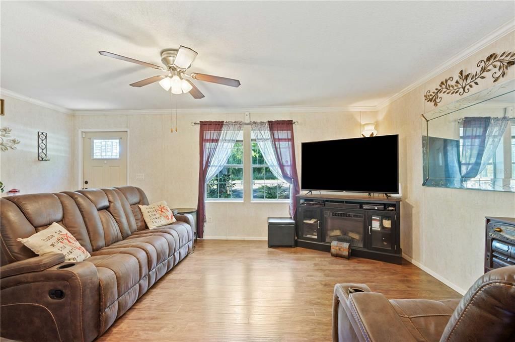 Living room has ceiling fan, laminate flooring, and is open with kitchen/dining area.