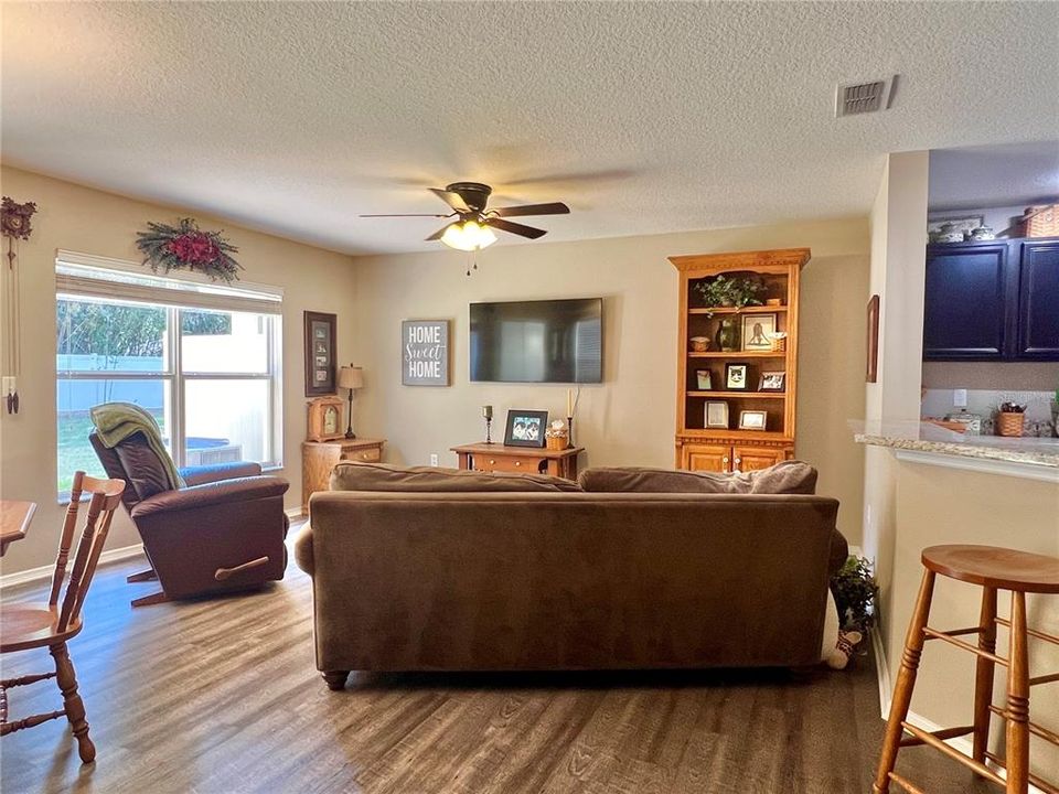 The great room features a newer lighted ceiling fan and a large window that overlooks the large backyard.