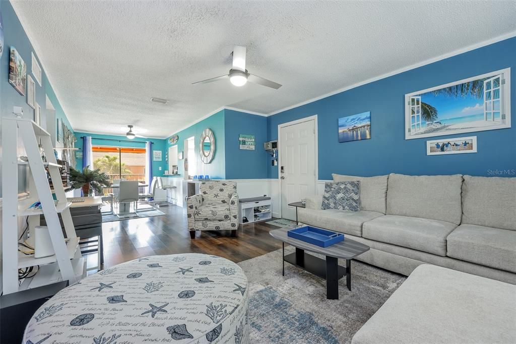 Living room featuring a textured ceiling, dark hardwood / wood-style floors, ornamental molding, and ceiling fan