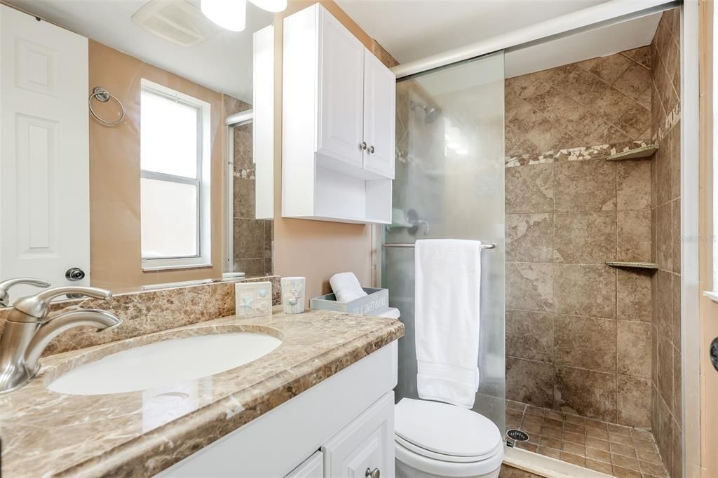 Bathroom with a shower with shower door, vanity, and toilet