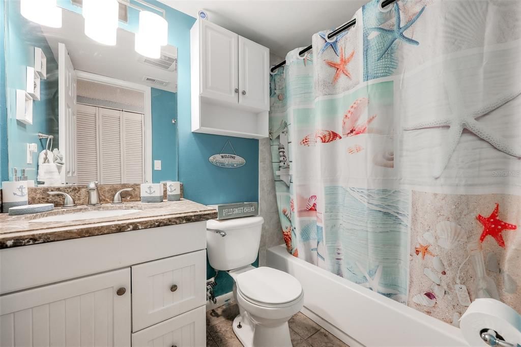 Full bathroom with tile floors, large vanity, toilet, and shower / bath combo with shower curtain