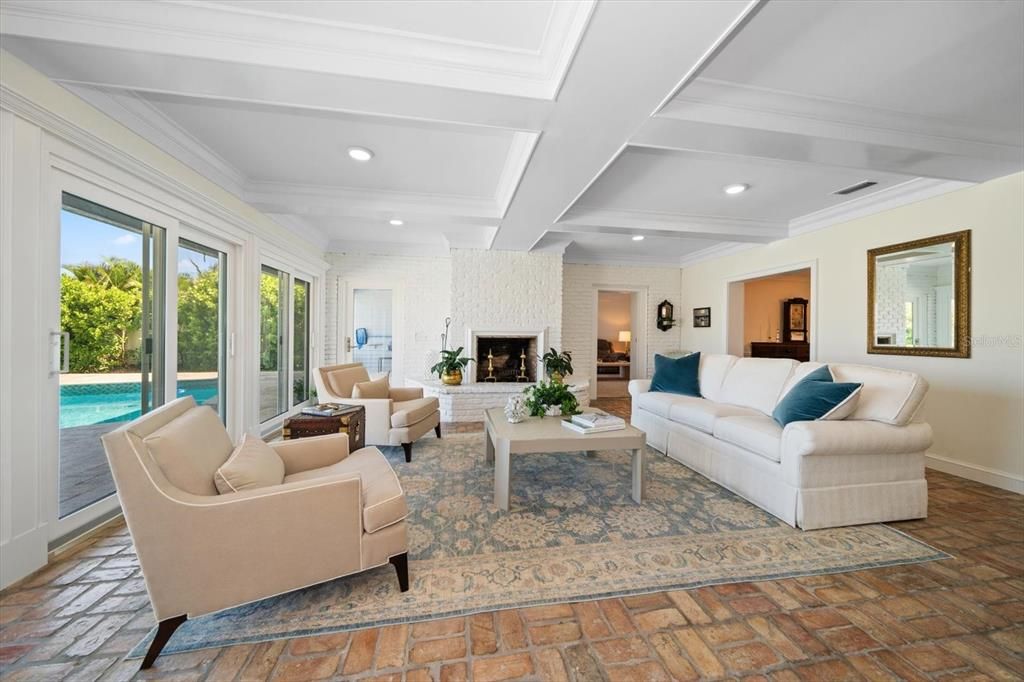 Great room area with attractive fireplace, flooring and coffered ceilings.