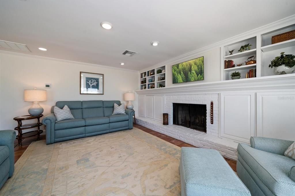 Attractive family room with built ins has a wood burning fireplace and extended hearth with intricate mantel.