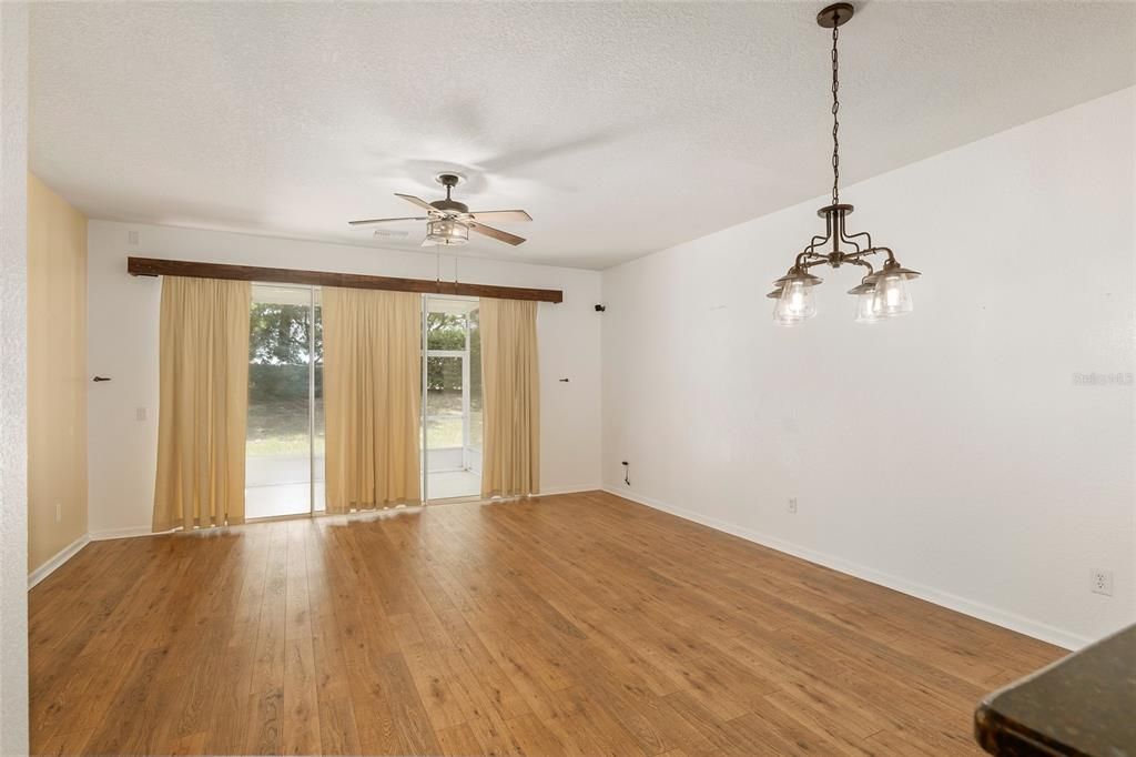 Living room with laminate flooring, triple sliders, and upgraded lighting