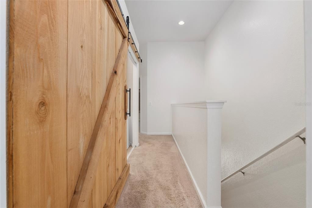 Upstairs hallway with custom barn door to laundry room