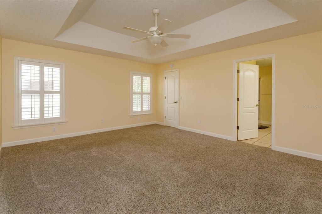 Primary Bedroom with tray ceiling and walk in closet in far corner, Ensuite Bath doorway