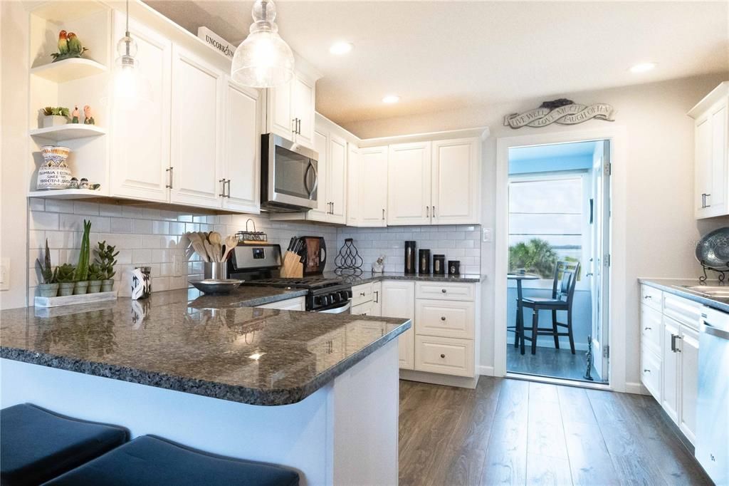 Updated kitchen with granite, loads of white cabinets, stainless appliances & pendant lights.