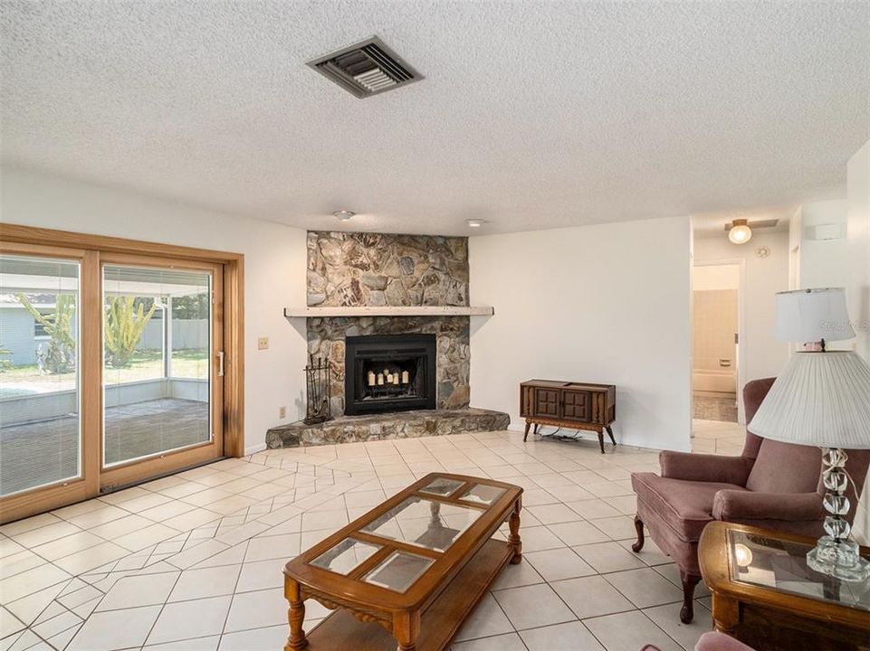 Stone fireplace warms the living room. Door leads outdoors.