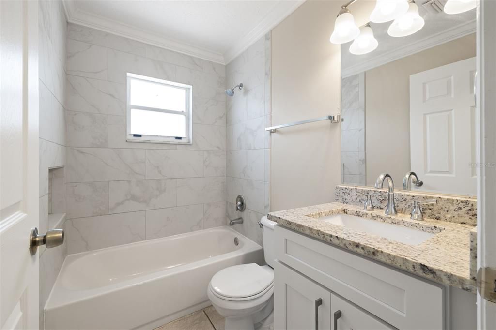 Hall bath is between bedrooms 2 and 3 with updated granite vanity and tile surround in the shower/tub combination.