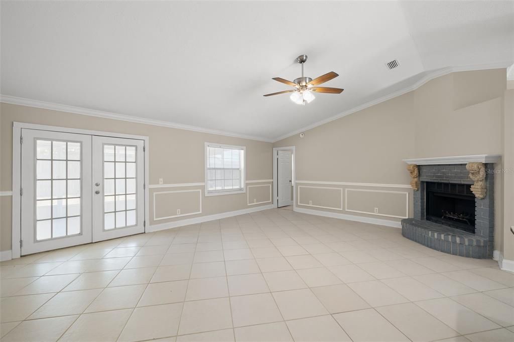 The great room has vaulted ceilings, a wood burning fireplace and french doors to the back porch. The door in the far corner is to the fourth bedroom.