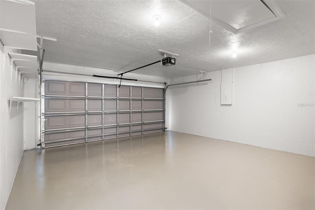 Newly painted floor in the two-car garage with attic access and garage door opener.