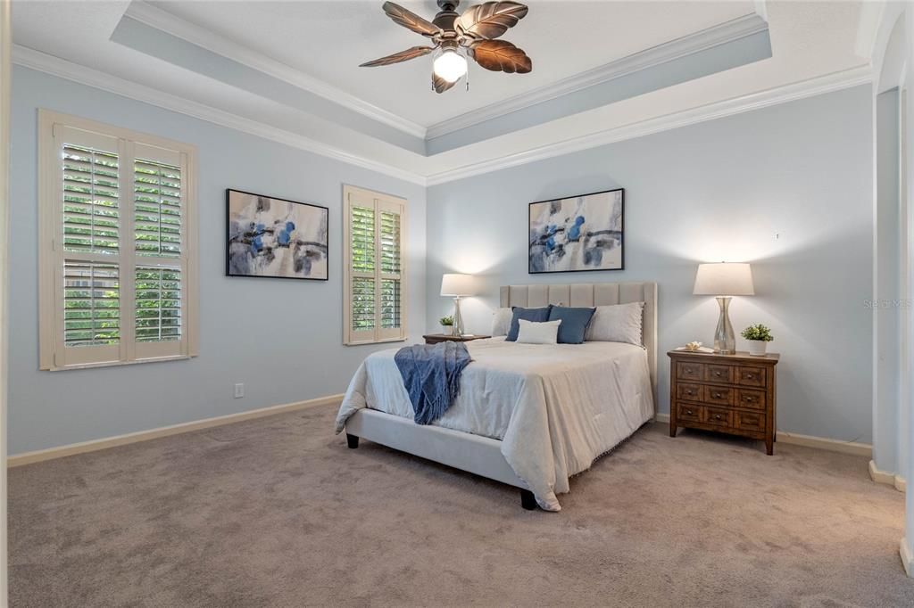 14' x 15' Primary Bedroom w/ tray ceiling, crown molding, ceiling fan & Plantation style shutters