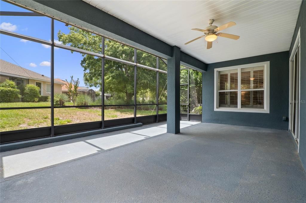 Screen enclosed covered patio w/ ceiling fan & roll-down shades