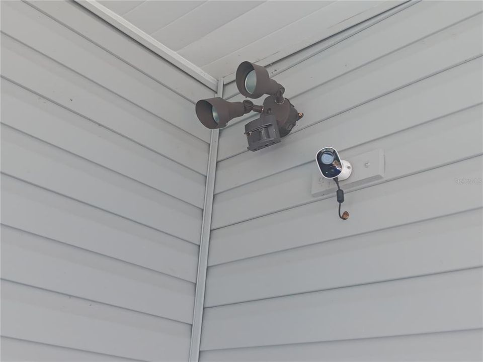 Home security camera that is near the tool shed in the carport.