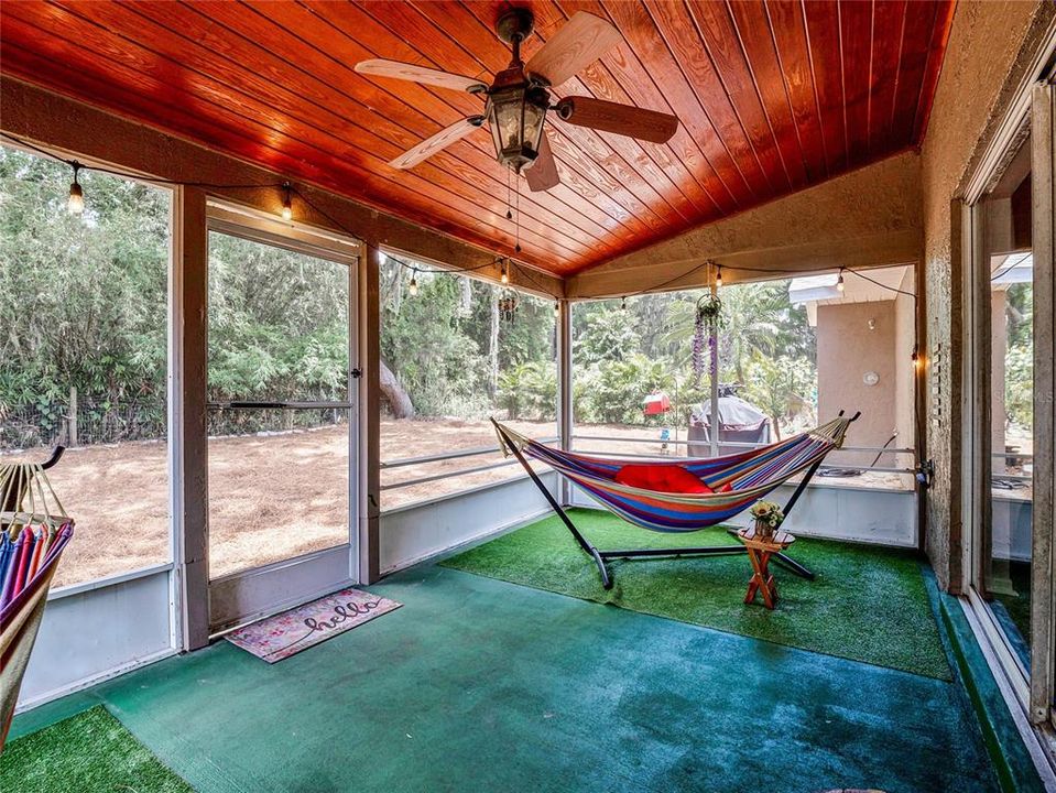 Large covered and screened lanai with wood slat wood ceiling.