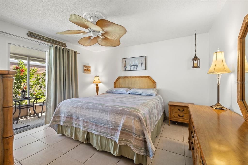 Large bedroom with plenty of room for a king size bed, coastal themed ceiling, walk-in closet with full size laundry, black-out shade, curtains and sliding door access to the screened-in lanai.