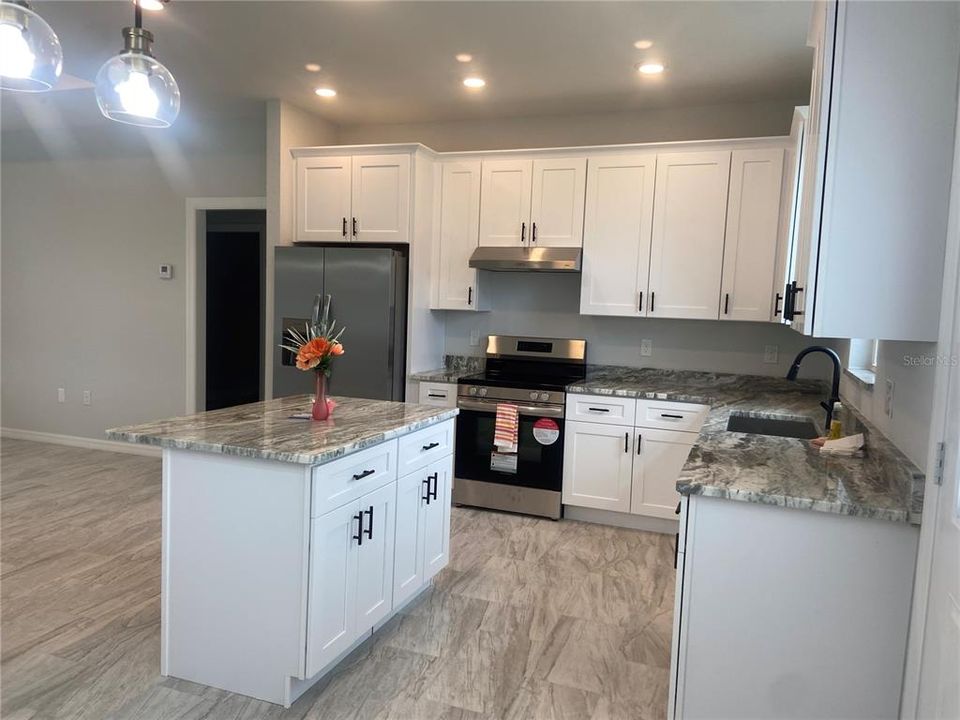 dining area to kitchen, island, crown at top of cabinets, recessed lights