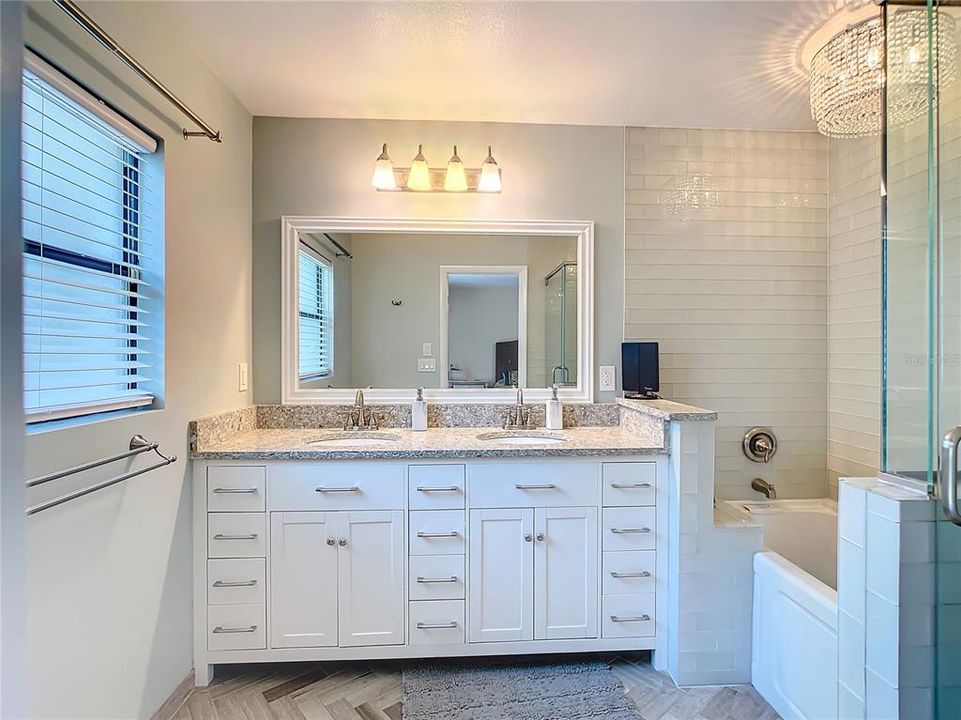 Beautifully remodeled Primary bath with double vanity sinks, herringbone tile, upgraded lighting and jacuzzi tub