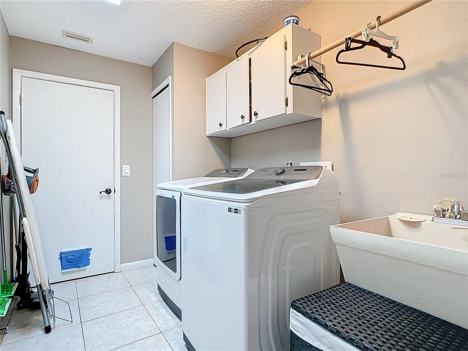 Indoor laundry off the garage with storage and utility sink.