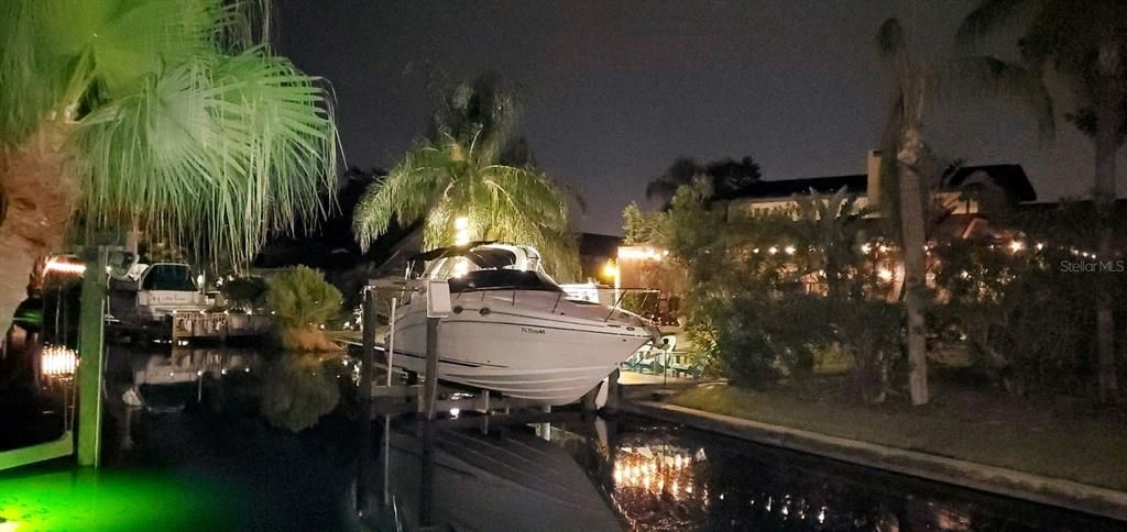 sellers boat in lift and view of backyard at night