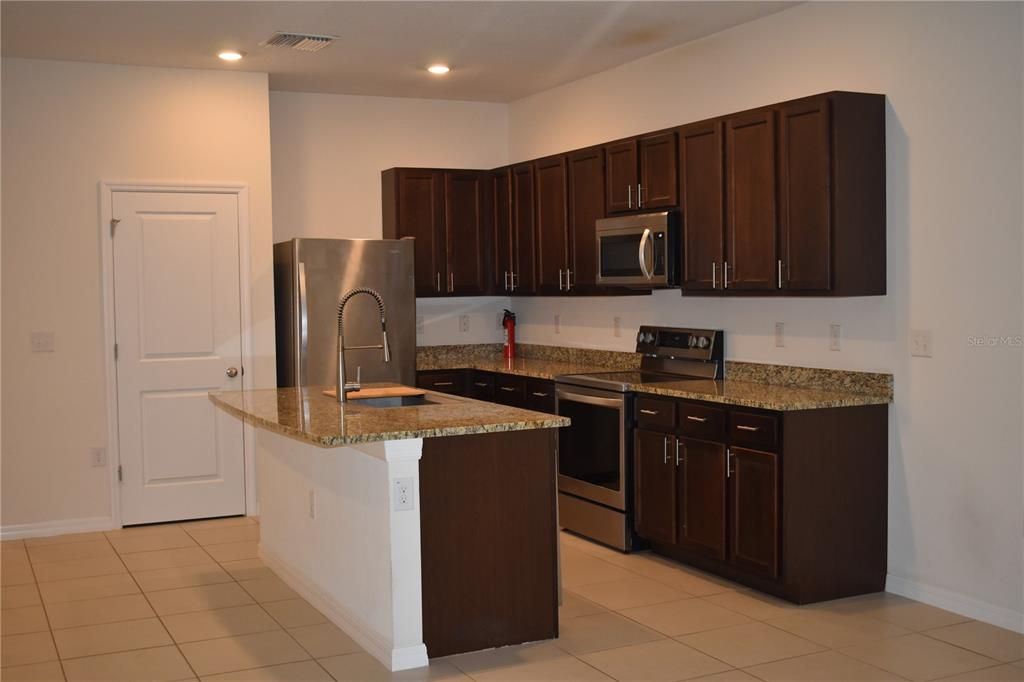 open spacious kitchen with wood cabinets and granite