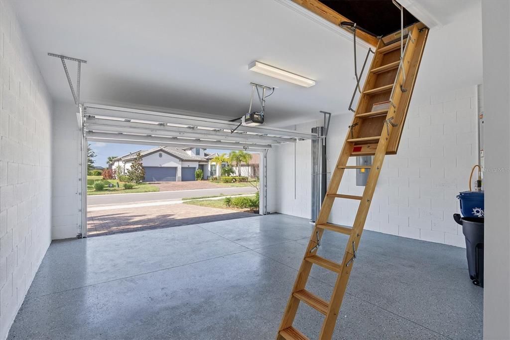 Generously-sized 2-car Garage with pulldown stairs to Attic and storage on reinforced flooring