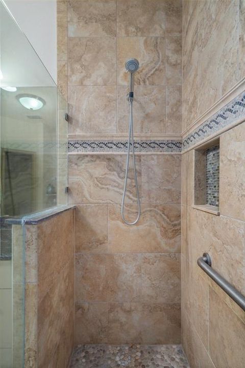 There are tall glass shower doors in this step-in shower