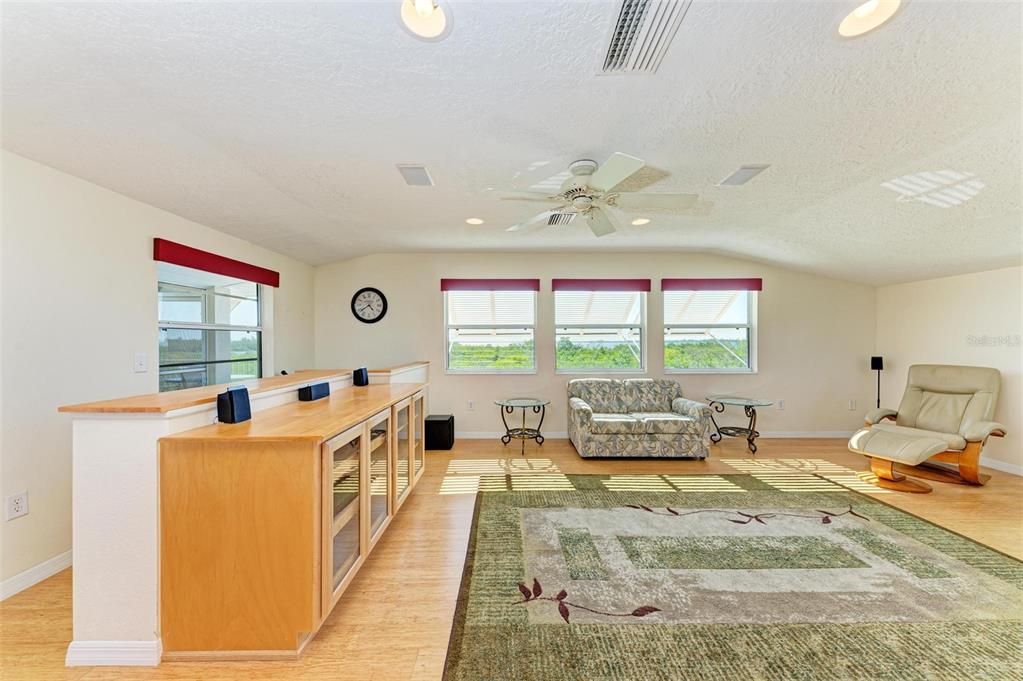 upstairs living room with entertainment center opens to kitchen.