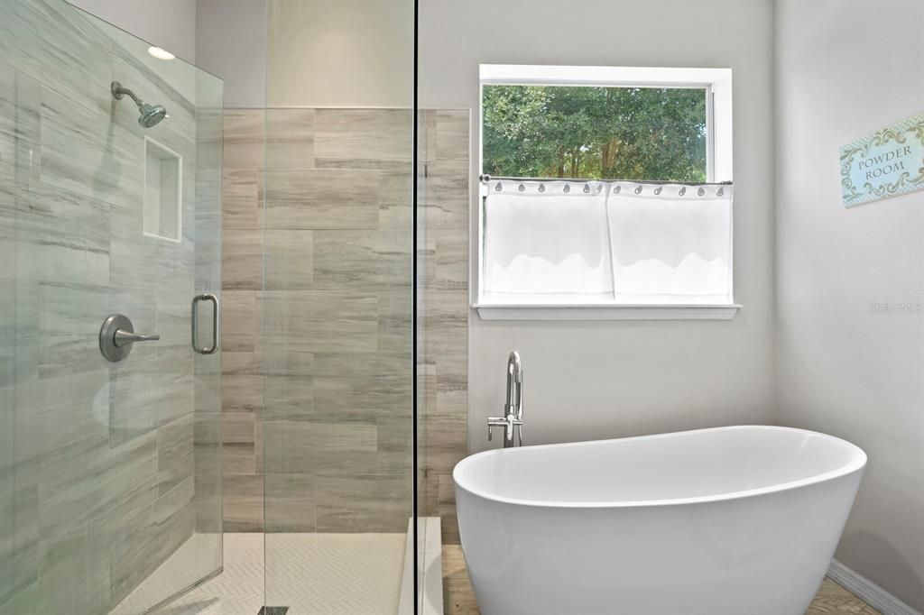 New primary bath includes frameless glass shower and freestanding bathtub