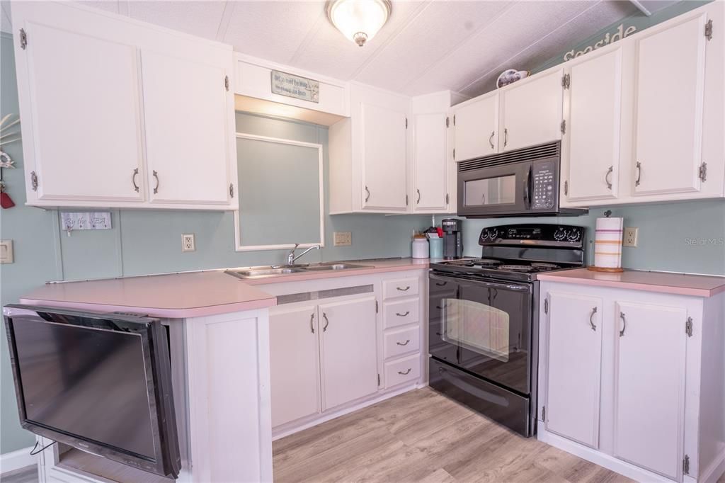 The kitchen features plenty of of cabinets and counter space, and wood laminate flooring.