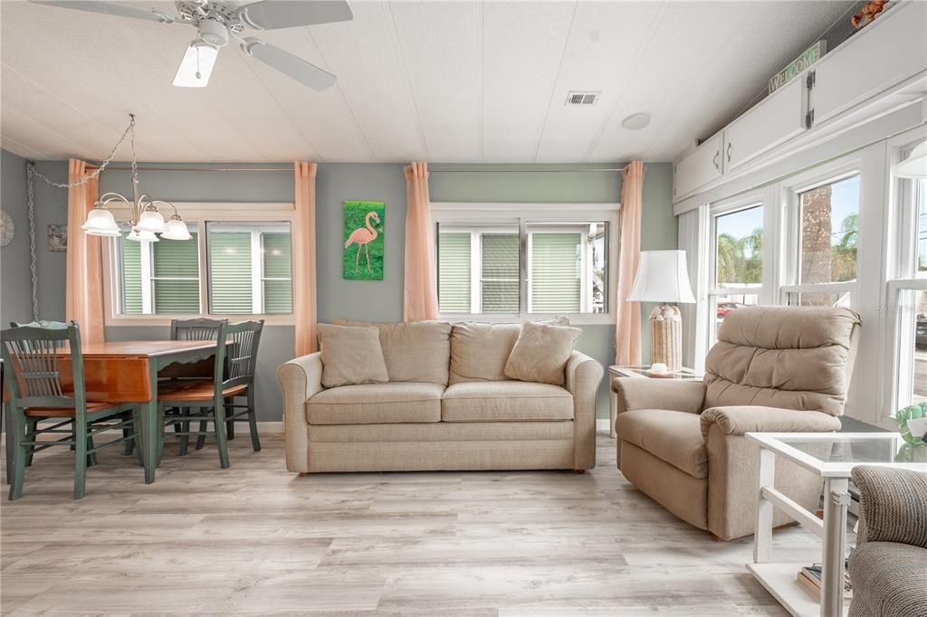 The living room features wood laminate flooring, and a ceiling fan for year-round comfort.