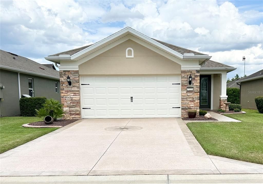 Front View of Home with Garage Door Down (no shadows), showcasing Upgraded Stacked Stone and Curbed Landscape Beds, with Premium Epoxied Driveway, Medallion & Walkway