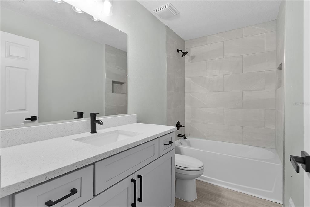 Guest bathroom with large vanity and tiled tub surround