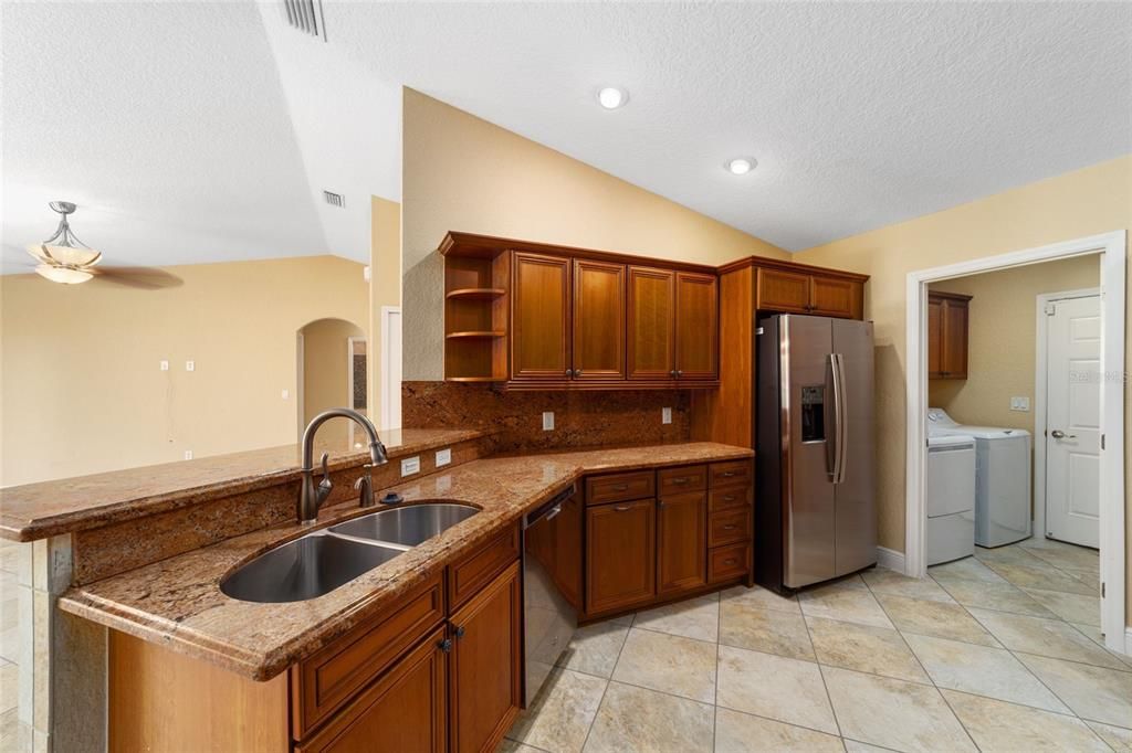 Kitchen with upgraded appliances, stone counters and wood cabinets. Entrance to the laundry room.