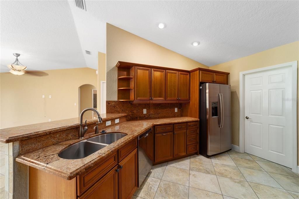 Kitchen with upgraded appliances, stone counters and wood cabinets.