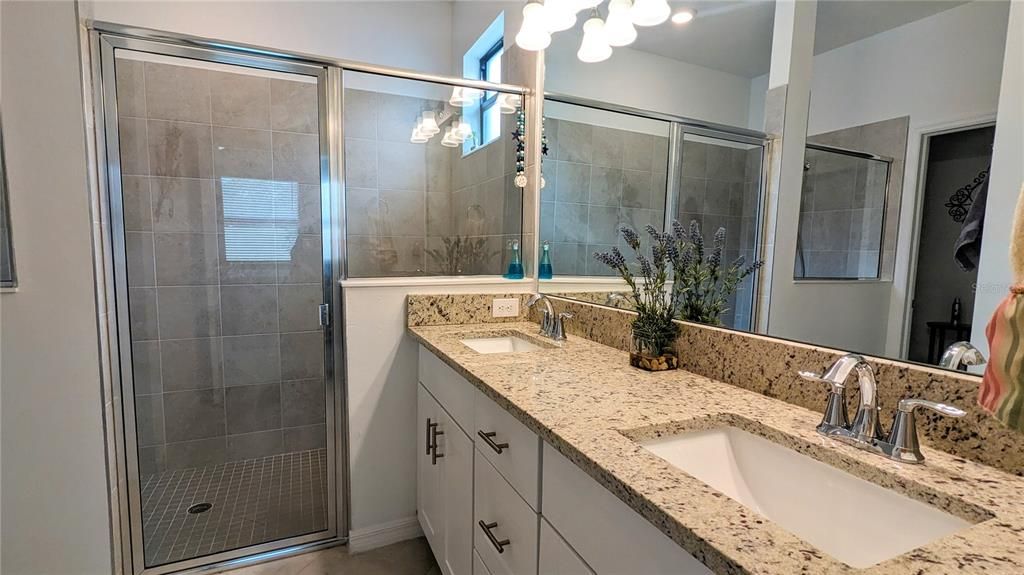 Primary bath with dual sinks, granite countertops, walk-in shower and private WC